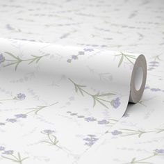 a white wallpaper with purple flowers and leaves on it's side, next to a roll of tape