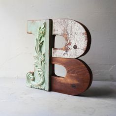 the letter b is made out of wood and has an ornate design on it's side