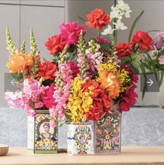 colorful flowers in small vases sitting on a table with greeting cards and card holders