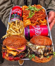 a tray with two hamburgers, fries and soda on it next to a can of coca cola