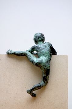 a bronze statue of a man kicking a soccer ball on top of a white block