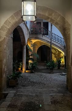 an archway with a light hanging from it's side and potted plants on the other side