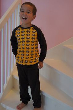 a young boy is standing on the stairs in his pajamas and smiling at the camera