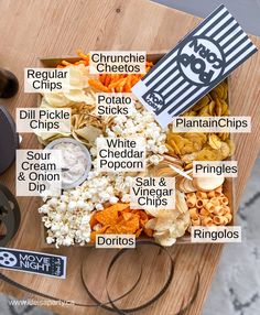 a wooden cutting board topped with lots of different types of snacks and condiments