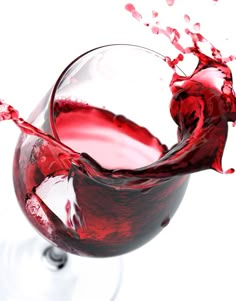 red wine being poured into a glass on a white background with splashing liquid in it