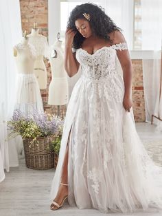 a woman in a white wedding dress standing next to mannequins and dresses