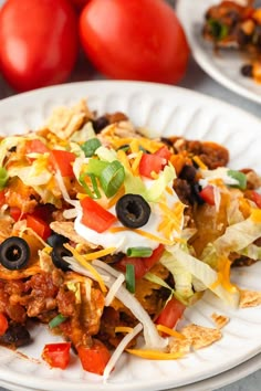 a white plate topped with taco salad on top of a table next to tomatoes