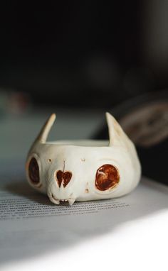 a white cat figurine sitting on top of an open book