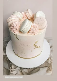 a white cake with pink frosting and macaroons on top