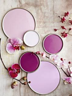 four different shades of pink and white paint with orchids on the table in front of them