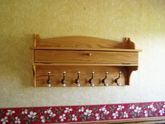 a wooden coat rack with five hooks on the wall next to a red and white flowered border