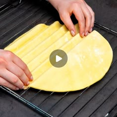 a person rolling out dough on top of an oven rack with one hand and the other