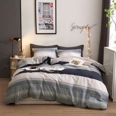 a bedroom with white walls and wooden flooring is decorated in grey and blue tones