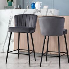 two grey velvet bar stools in front of a counter