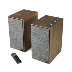 two wooden speakers with remote control on white background