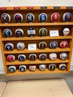 a display case with baseballs on it in front of a white wall and wooden bench