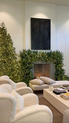 a living room filled with white couches and christmas trees in the corner, surrounded by greenery