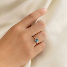 a woman's hand wearing a ring with a blue topazte on it