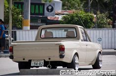 an old truck is parked on the side of the road in front of some people