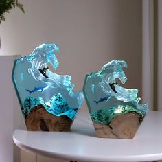 two vases sitting on top of a white table next to each other with blue waves in them