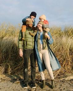 three people are standing in the sand with their arms around each other and one person is holding two children