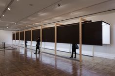 people are standing in front of large black and white screens on the wall, with one person looking at them