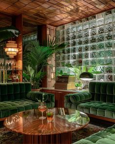 a living room filled with green couches next to a tall window covered in glass blocks