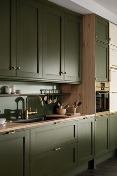 a kitchen with green cabinets and wooden counter tops