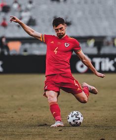 a man kicking a soccer ball on top of a field