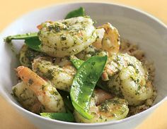 a white bowl filled with shrimp and green vegetables on top of a yellow tablecloth