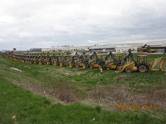 there are many tractors that are parked in the grass near each other on this field