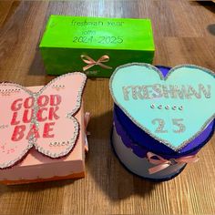 two heart shaped cakes sitting on top of a wooden table next to boxes filled with treats