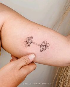 a woman's arm with two flowers on it and a barbell in the middle