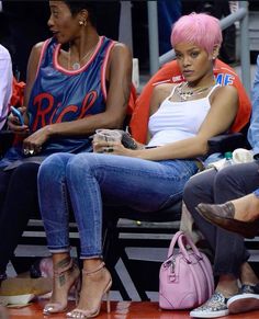 two women with pink hair sitting next to each other at a basketball game in the stands