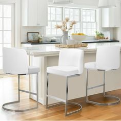 two white bar stools sitting at an island in a kitchen