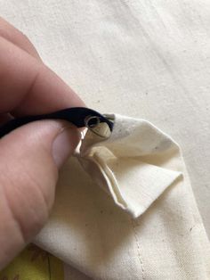 someone is cutting fabric with scissors on a piece of white material that has been sewn together