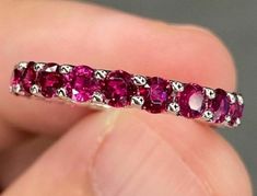 a close up of a person holding a ring with pink stones on the inside of it