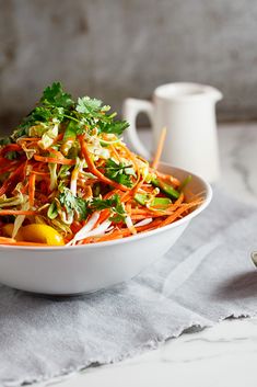 a white bowl filled with carrots and veggies on top of a table