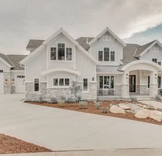 a large white house with lots of windows on it's sides and landscaping around the front yard