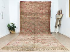 an old rug is sitting on the floor next to a potted plant in a corner