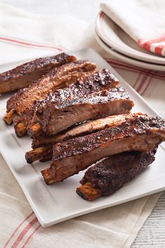 some ribs are on a white plate with powdered sugar and pepper sprinkled on top