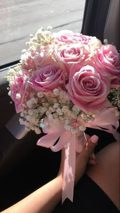 a bouquet of pink roses and baby's breath sits in the passenger seat of a car