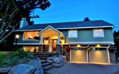 a large house with two garages and lights on the front door at night time