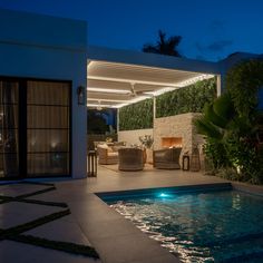 an outdoor living area next to a pool at night