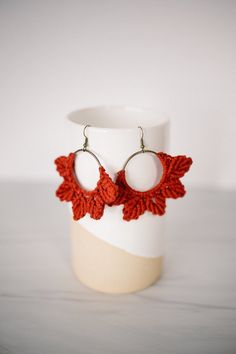 red crocheted leaves are attached to the back of a pair of hoop earrings