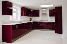 an empty kitchen with red cabinets and white flooring