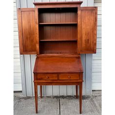 an old wooden desk and hutch sitting on the side of a building in front of a garage door