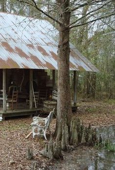 an old cabin sits in the woods next to a creek