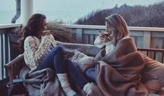 two women sitting on a porch next to each other with newspapers and candles in front of them