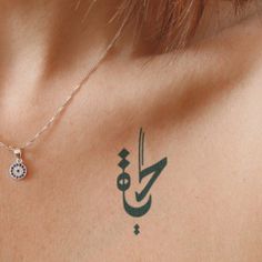 the back of a woman's shoulder with arabic writing and a small blue diamond on it